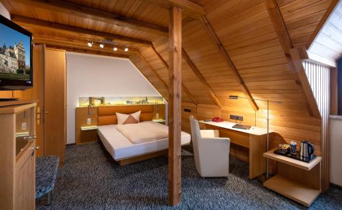 a bedroom with a bed and a tv in a room at Hotel Simonshof in Wolfsburg