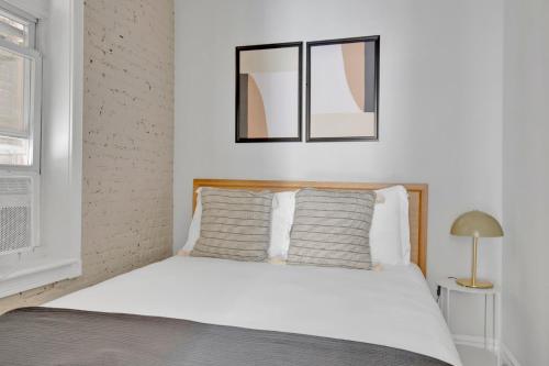 - une chambre avec un lit blanc et 2 fenêtres dans l'établissement Beautiful W Village 1BR nr 1 train NYC-888, à New York