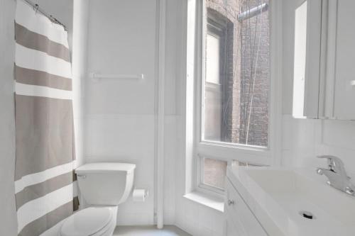 une salle de bain blanche avec toilettes et fenêtre dans l'établissement Beautiful W Village 1BR nr 1 train NYC-888, à New York