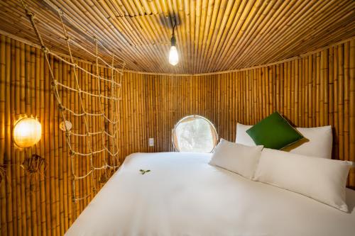 sypialnia z białym łóżkiem w drewnianej ścianie w obiekcie Cocohut Hoi An Homestay w Hoi An