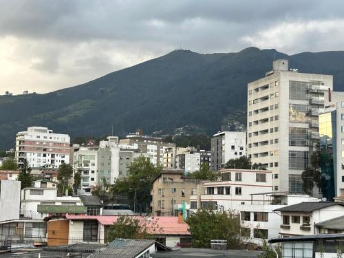 eine Stadt mit Gebäuden und einem Berg im Hintergrund in der Unterkunft IÑAQUITO GOLD in Quito
