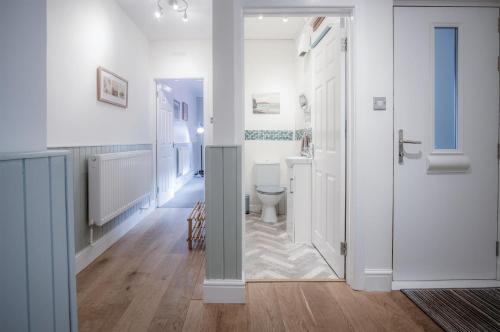 baño blanco con aseo y pasillo en Glenvale - 2 Bedroom Apartment - Saundersfoot, en Saundersfoot