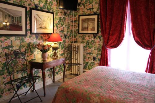 a bedroom with a bed and a table with a lamp at Hôtel De Nice in Paris