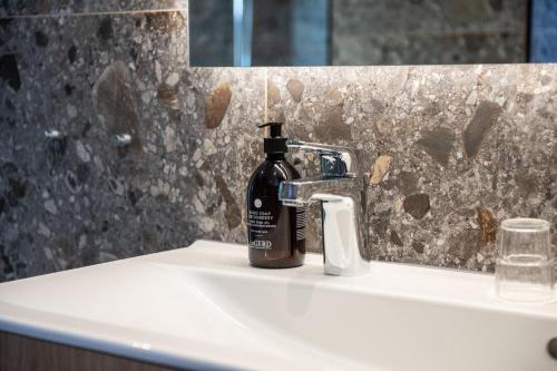a black bottle of soap sitting on a bathroom sink at Medlefors Hotell & Konferens in Skellefteå