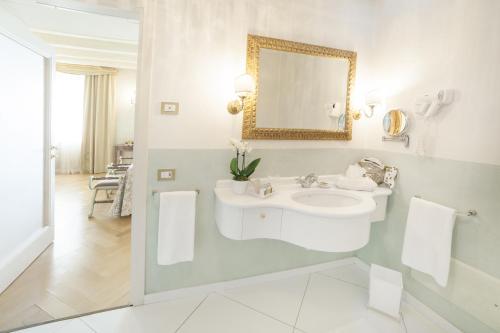 a white bathroom with a sink and a mirror at Relais Fra' Lorenzo in Verona