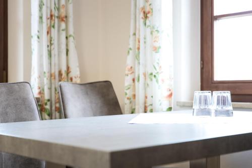 twee glazen zittend op een tafel met stoelen bij Landhaus Vier Jahreszeiten in Eriskirch