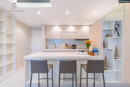 a kitchen with a large white island with four chairs at Park view Avalon Apartment District 1 HCM City in Ho Chi Minh City