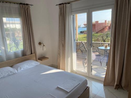 a bedroom with a bed and a balcony with a view at sofia guesthouse in Nea Skioni