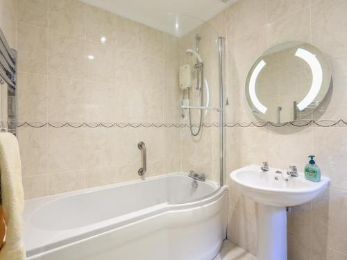 a bathroom with a white tub and a sink at 2 Channel View in Salcombe