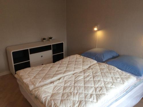 a bedroom with a large bed with two blue pillows at Axelgaard Guest Rooms in Ovtrup