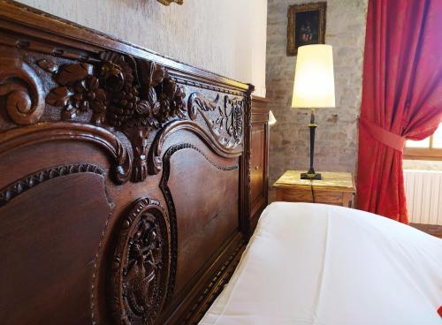 a large wooden bed in a bedroom with a lamp at Hôtel Le Manoir De Mathan Crépon à la campagne 5 mn d'Arromanches et 10 mn de Bayeux in Crépon