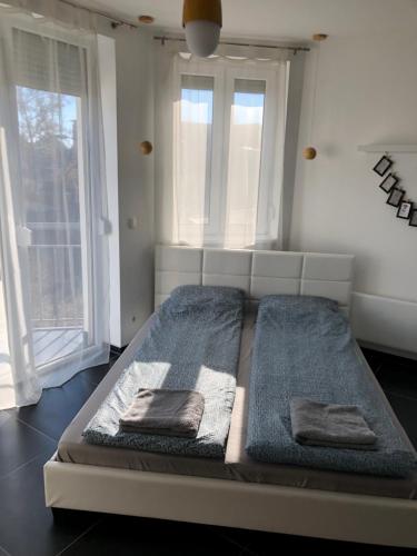 uma cama com duas almofadas num quarto com janelas em Kiad-Lak Apartman em Szeged