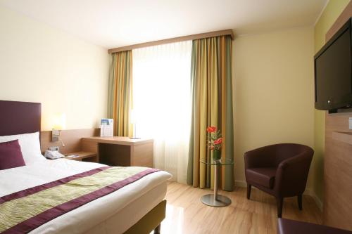 a hotel room with a bed and a chair at Congress Hotel am Stadtpark in Hannover