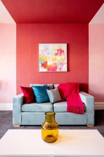 a living room with a couch against a red wall at Charles Alexander Short Stay - Botanical House in Cleveleys