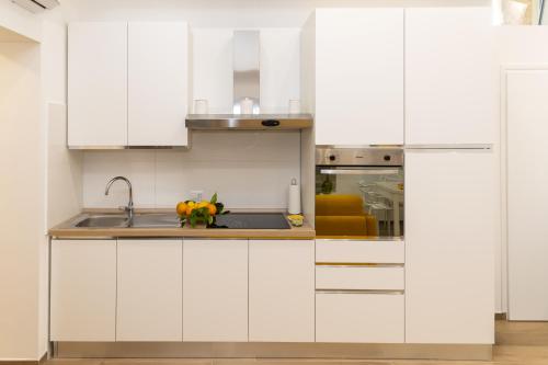 a kitchen with white cabinets and a sink at Mirasole House in Massa Lubrense