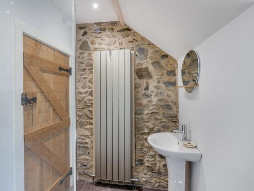 a bathroom with a sink and a stone wall at Ivy Bush Cottage in Llanddewi-Brefi
