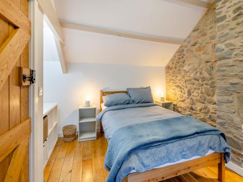 1 dormitorio con cama y pared de piedra en Ivy Bush Cottage, en Llanddewi-Brefi