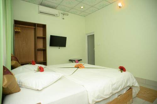 a bedroom with a large white bed with flowers on it at Summer Vibes Beach Front in Rasdu