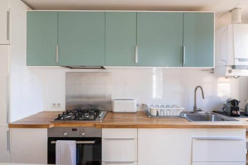 a white kitchen with blue cabinets and a sink at BEL APPARTEMENT DANS LE CENTRE D'AVIGNON in Avignon