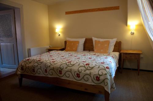 ein Bett in einem Zimmer mit zwei Nachttischen und zwei Tischen in der Unterkunft Hotel am Hoken in Quedlinburg