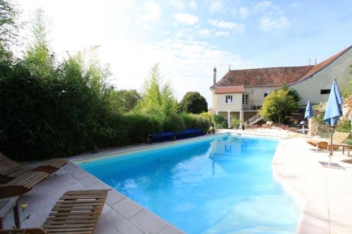 a large blue swimming pool with chairs and a house at LE PRIEURE DE BUFFON in Buffon