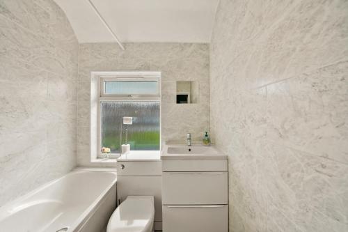 baño blanco con bañera, lavamanos y bañera tubermott en Large House with Parking and Garden - Sleeps 7, en Kent