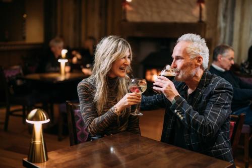 a man and woman sitting at a table drinking wine at The Valley Hotel & Carriage Gardens in Fivemiletown