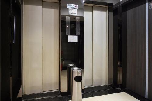 a hallway with two elevators in a building with a trash can at Hygge House in Hong Kong