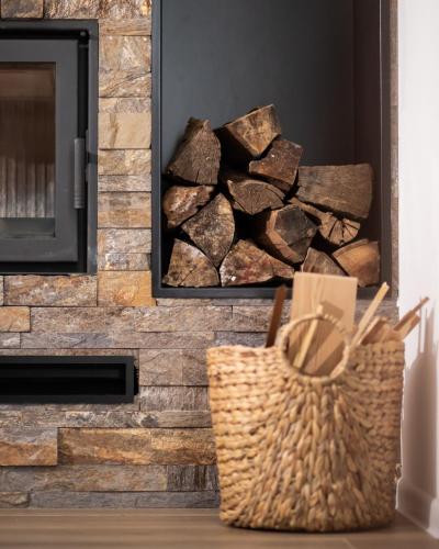a pile of fire wood in a fireplace with a basket at Tarvil Apartmani - Zaovine in Bajina Bašta