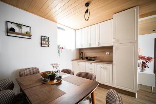 a kitchen and dining room with a wooden table and chairs at Tarvil Apartmani - Zaovine in Bajina Bašta