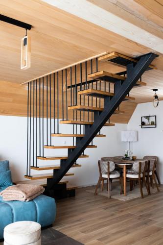 a wooden staircase in a living room with a table at Tarvil Apartmani - Zaovine in Bajina Bašta