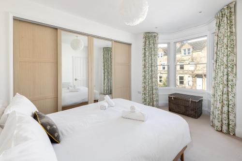 a white bedroom with a large bed and a window at Fabulous House - Only 10 minutes walk to Roman Baths in Bath