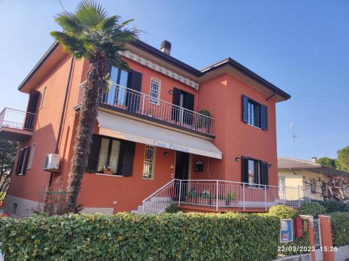 un edificio rojo con una palmera delante en Casa Patrizia B&B cir in info, en Sirmione