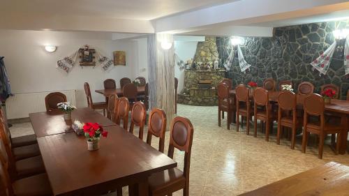 una sala da pranzo con tavoli e sedie in legno di Cabana Perla Munților - Valea Doftanei a Podu lui Neag