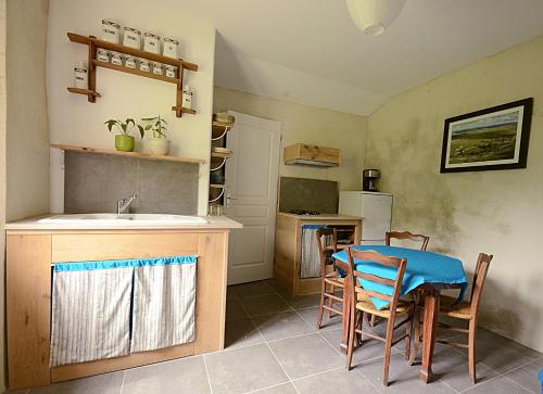- une cuisine avec une table, des chaises et un évier dans l'établissement La ferme du Chant de Cailloux, à Die