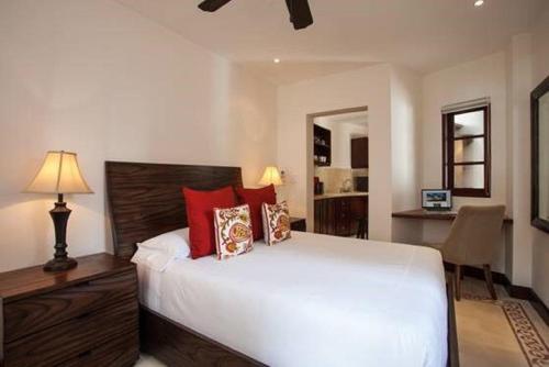 1 dormitorio con 1 cama blanca grande con almohadas rojas en Las Catalinas - Studio Cazenovia centrally located, short walk to beach, en Playa Danta