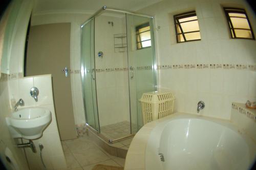 a bathroom with a shower and a tub and a sink at The Third Dolphin in Herolds Bay