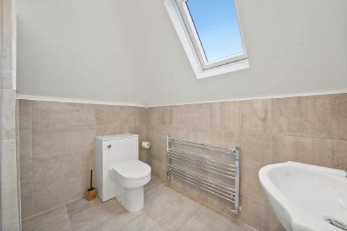 uma casa de banho com um WC, um lavatório e uma janela em Fantastic Maidstone Flat - Sleeps 4 em Kent