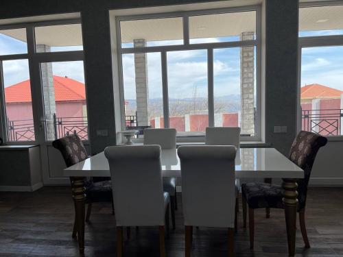 a dining room with a table and chairs and windows at Shamakhi Villa in Shamakhi
