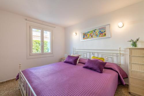 una camera da letto con un letto con lenzuola viola e una finestra di Villa Mercuri a Alcudia