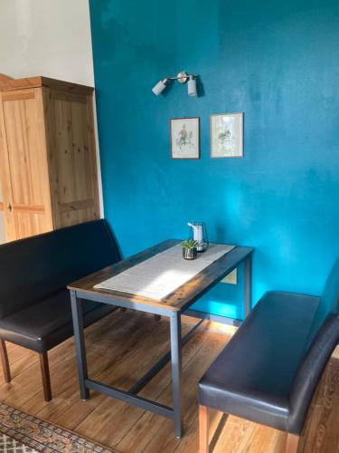 stół i 2 krzesła w pokoju z niebieską ścianą w obiekcie Apartment Schloss Benrath w mieście Greifswald