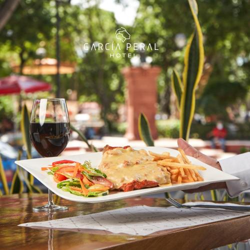 a plate of food on a table with a glass of wine at Hotel Garcia Peral in Huajuapan de León