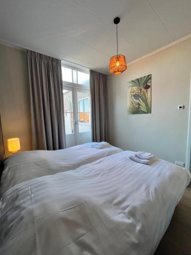 een groot wit bed in een kamer met een raam bij De Molen in Zierikzee