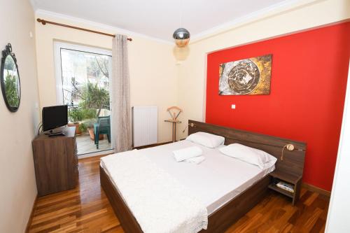 um quarto com uma cama com uma parede vermelha em Joyia's Apartment em Zakynthos Town