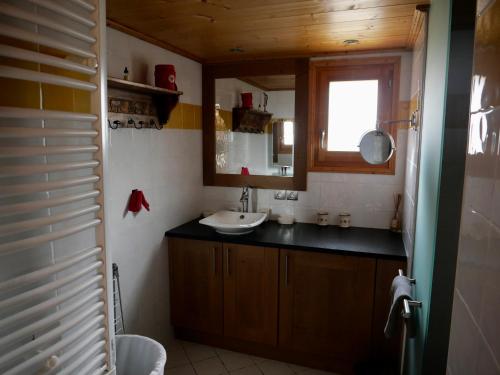 a bathroom with a sink and a mirror and a window at Résidence Les Chardons Argentés in Samoëns