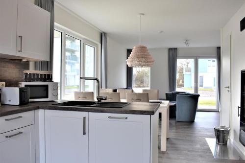 uma cozinha com armários brancos e uma sala de estar em Haus Nr 16, Ferienhaus Deichgraf em Wangerland