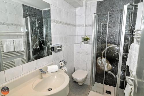 a bathroom with a sink and a toilet and a shower at Flairhotel am Wörthersee in Velden am Wörthersee