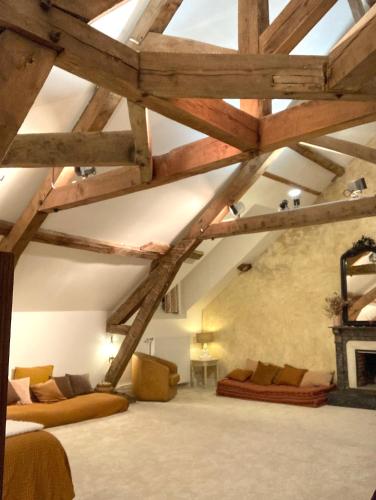 an attic room with wooden beams and couches and a fireplace at Maison d'hôtes La Doucelle culture et bien-être in Lignieres-Orgeres