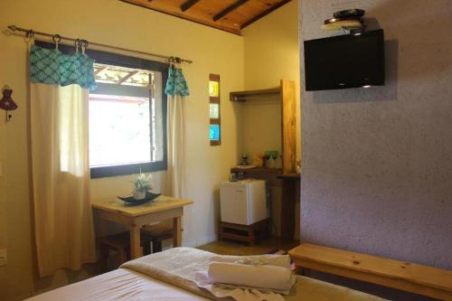 a bedroom with a bed and a desk and a window at Pousada Luar do Cipó in Serra do Cipo