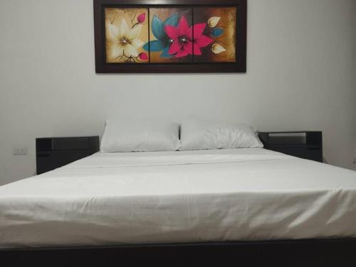 een wit bed in een kamer met een schilderij aan de muur bij Apartamento el mirador in Melgar